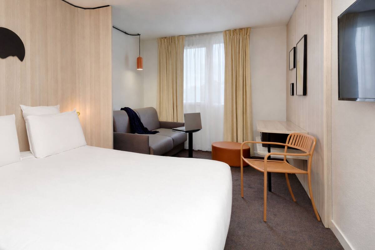 Una habitación de hotel con una cama, un sofá, un escritorio y una silla.