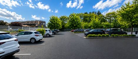 A parking lot with cars, trees, and a building in the background.