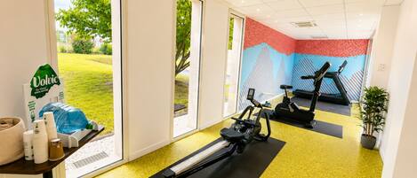 A gym with exercise equipment, a treadmill, and a stationary bike.