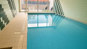 A swimming pool with tiled walls and a clear view of the outside.