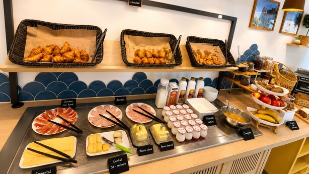 Un bufé con diversos alimentos, como cruasanes, carnes, quesos y frutas.