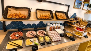 A buffet with various food items, including croissants, meats, cheeses, and fruits.