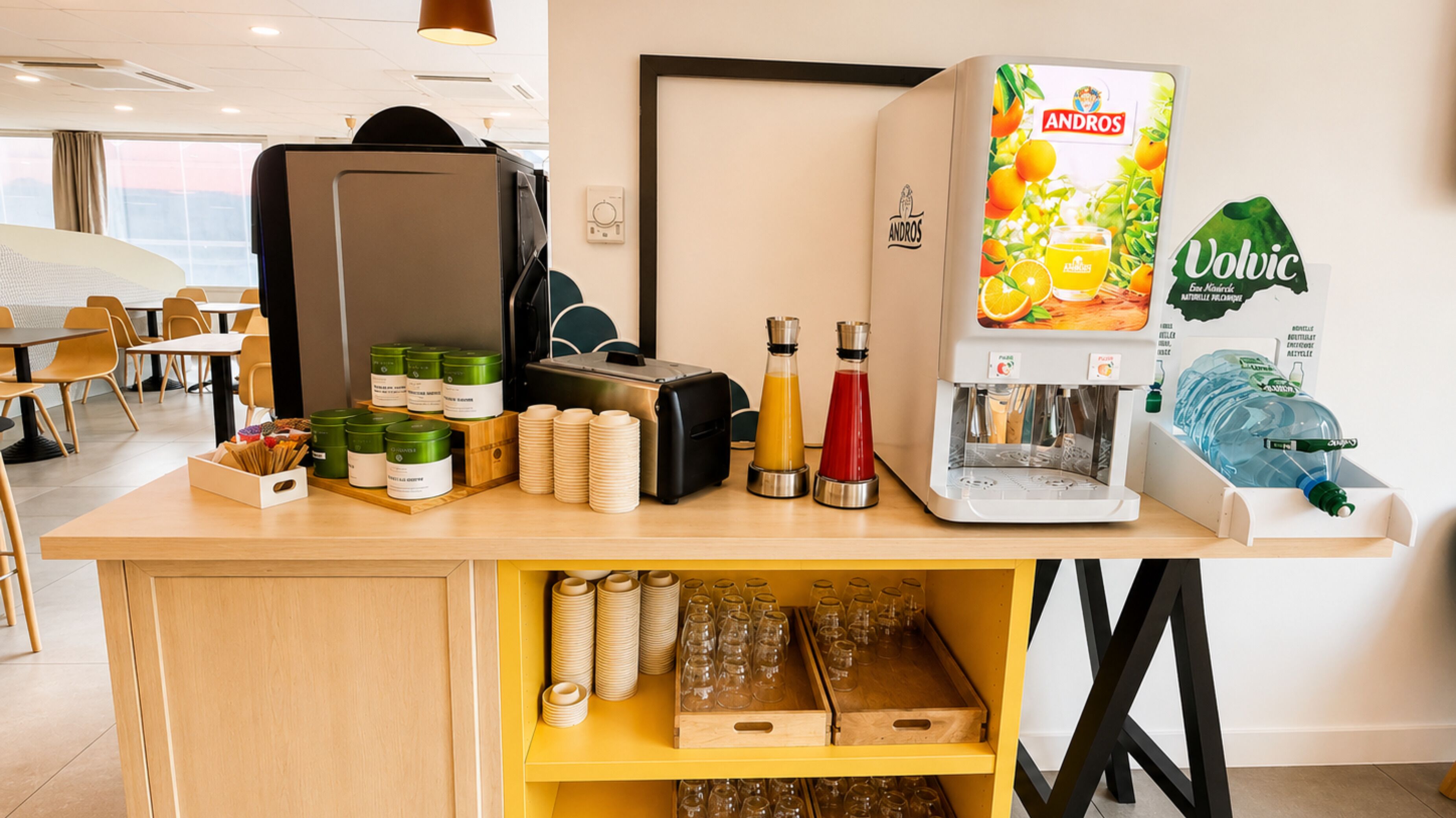 A self-service beverage station with a coffee machine, juice dispenser, and water dispenser.