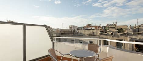 A rooftop terrace with a table and chairs, offering a view of the cityscape.