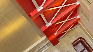 A modern interior with a geometric red structure, a tiled floor, and leather seating areas. - Aramunt Apartments (Barcelona)