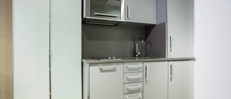 A compact kitchen with a microwave, sink, and cabinets.