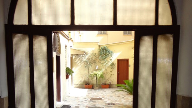 An arched doorway leading to a courtyard with tiled flooring and potted plants. - Città Eterna Bed & Breakfast (Rome)