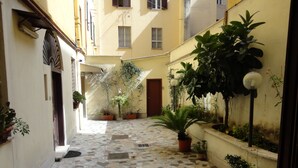 A narrow alley with tiled flooring, potted plants, and a building entrance. - Città Eterna Bed & Breakfast (Rome)