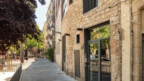 A stone building with a modern entrance, a narrow sidewalk, and a tree-lined street.