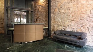A reception area with a stone wall, a reception desk, a sofa, and a glass partition.