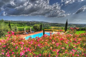 A pool surrounded by vibrant flowers, with a view of rolling hills and a cloudy sky. - Tenuta Cusmano Villa Resort (Grottaferrata)