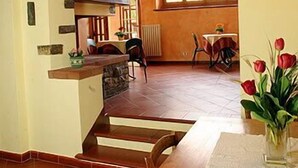 A dining area with a table and chairs, a staircase leading to an upper level, and a window with a view. - Il Colombaino (Scandicci)