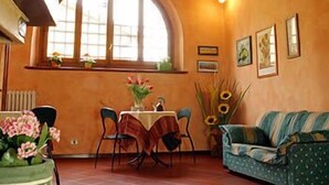 A cozy room with a dining table, chairs, a sofa, and a large arched window. - Il Colombaino (Scandicci)