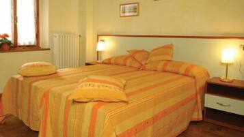 Una cama doble con ropa de cama a rayas, una mesita de noche con lámpara y una ventana con cortinas.