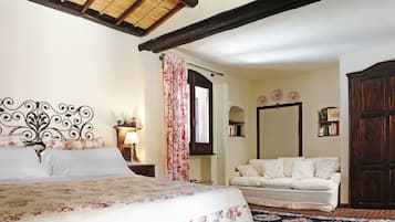 A bedroom with a bed, a nightstand, a dresser, a window with curtains, and a sofa.