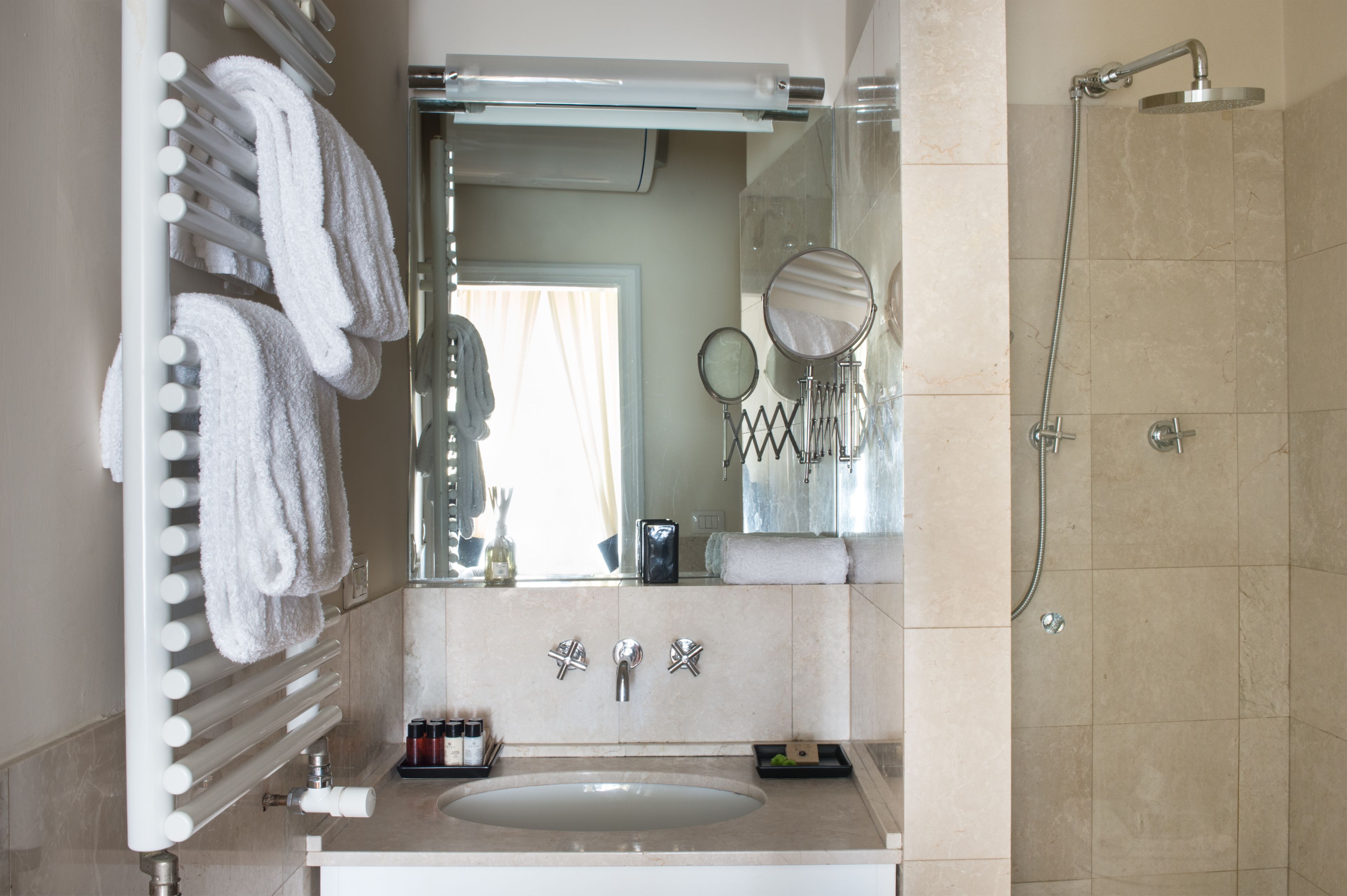 Un baño con lavabo, espejo, toallero y ducha.