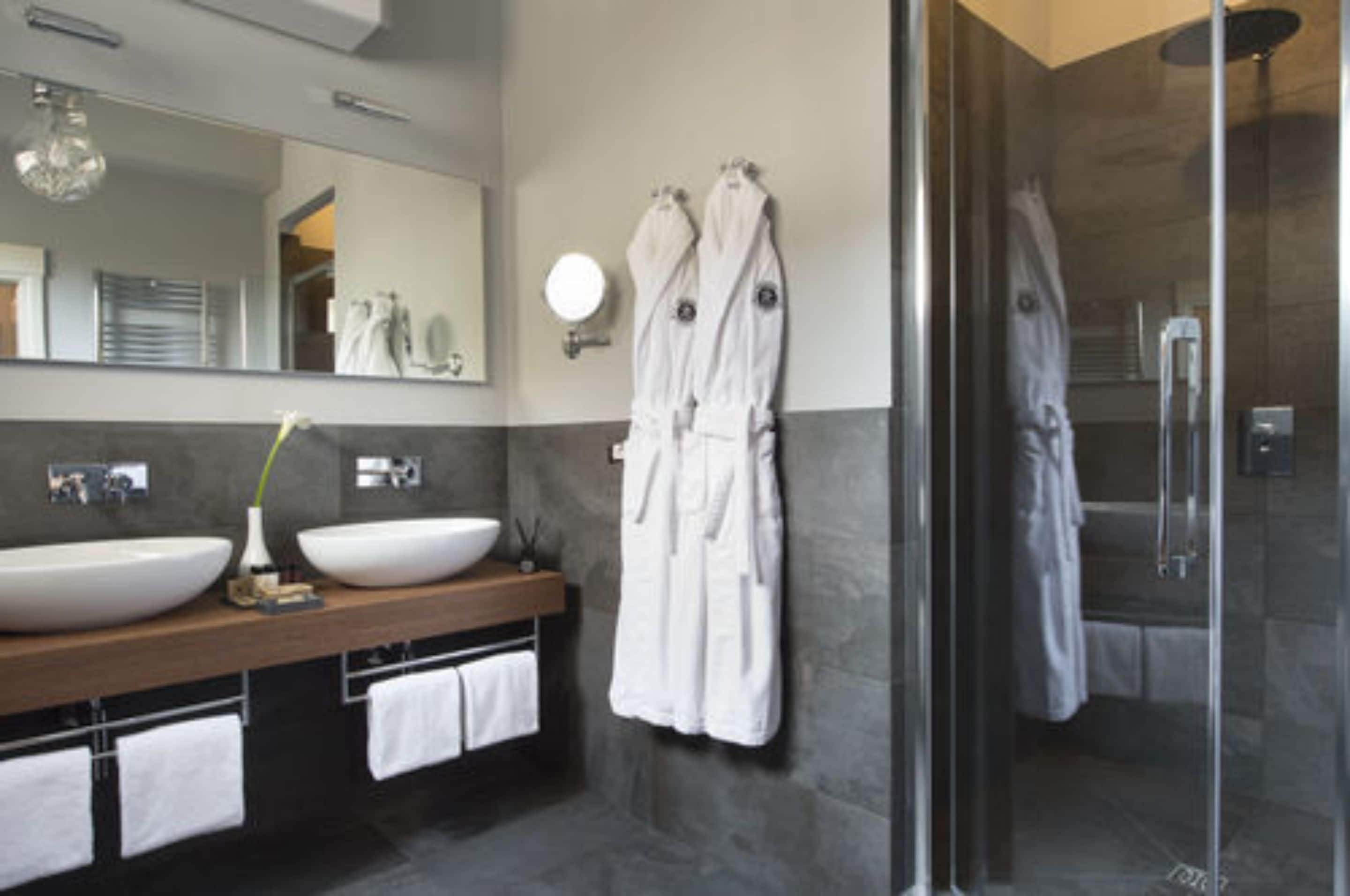 A modern bathroom with two large sinks, a mirror, and a glass-enclosed shower area.