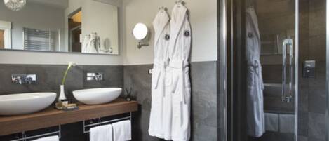 A modern bathroom with two large sinks, a mirror, and a glass-enclosed shower area.