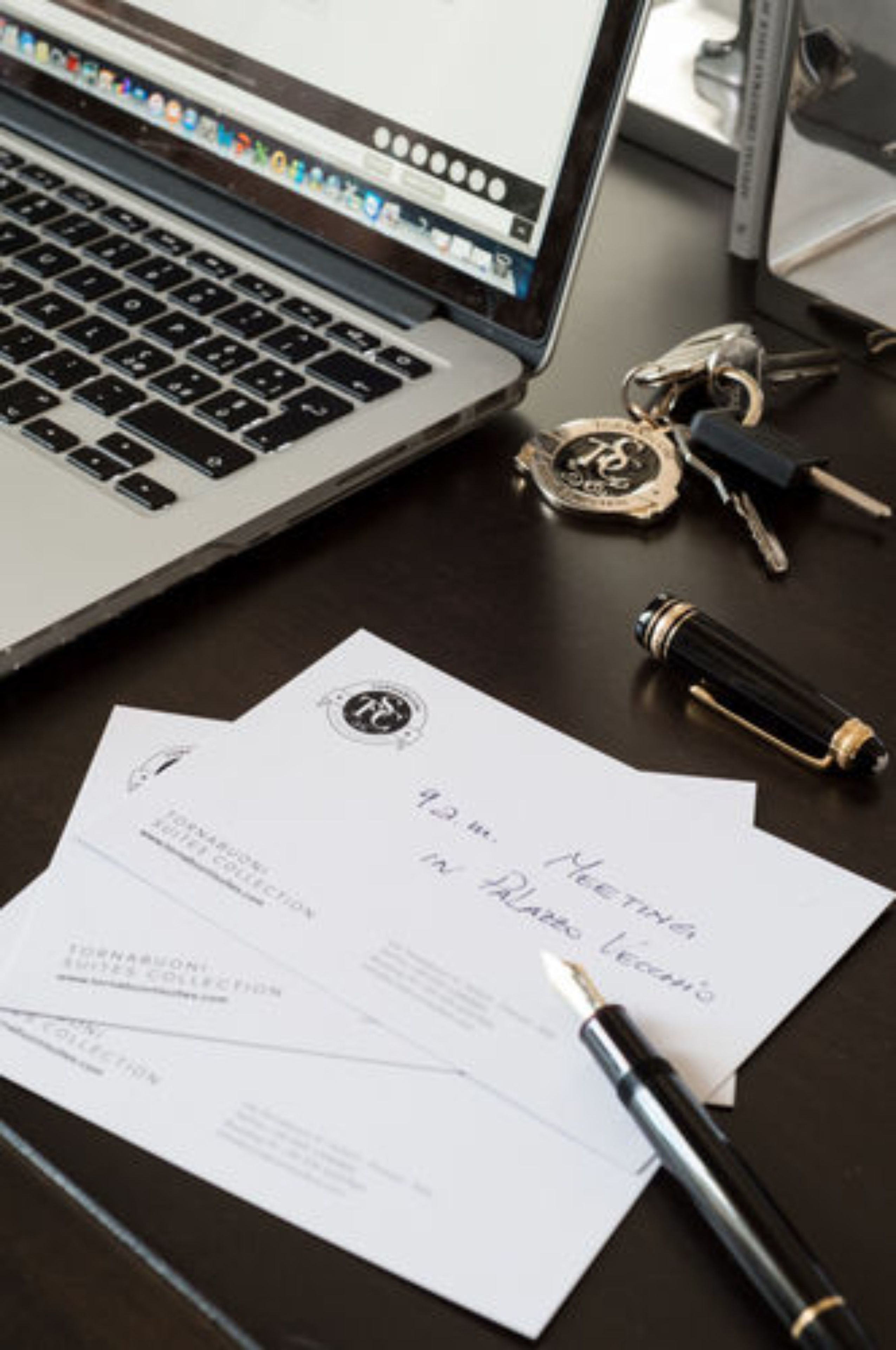 A laptop, keys, a fountain pen, and a document on a desk.