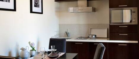 A modern kitchen with dark wooden cabinets, a stainless steel microwave, and a dining area with a table set for two.