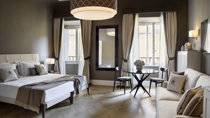 Habitación de hotel con una cama grande, un sofá, una mesa de comedor y una araña.