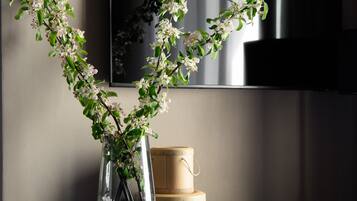 A wooden table with a vase of flowers, a book, and stacked containers.