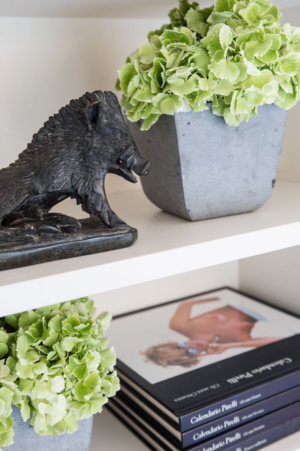 Una estantería con una escultura metálica decorativa, una planta en maceta y una pila de libros.