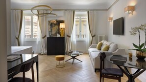 Una sala de estar moderna con una mesa de centro de vidrio, un sofá, un comedor con una mesa y sillas, y un cuadro grande en la pared.