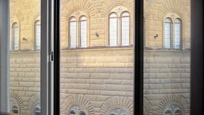 Fachada de edificio con ventanas de arco y mampostería de piedra.