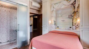 A hotel room with a bed, a bathroom with a shower, and a hallway leading to another room. - 38 Viminale Street Deluxe (Rome)