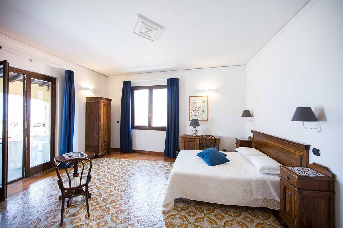 Ein Hotelzimmer mit Bett, Stuhl, Schreibtisch, Kleiderschrank und einem Fenster mit Vorhängen.