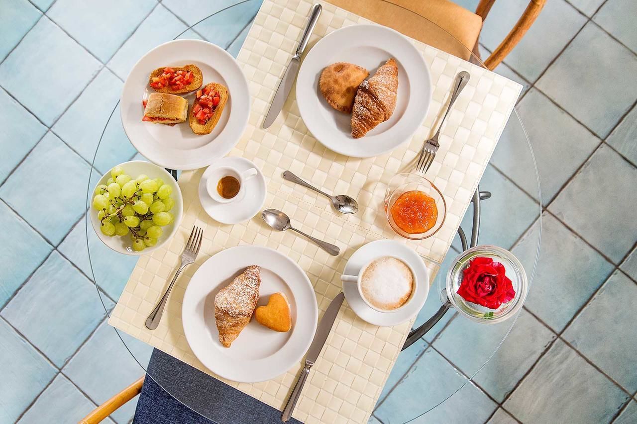 A table set with plates of food, a bowl of grapes, a cup of coffee, and a glass of jam.