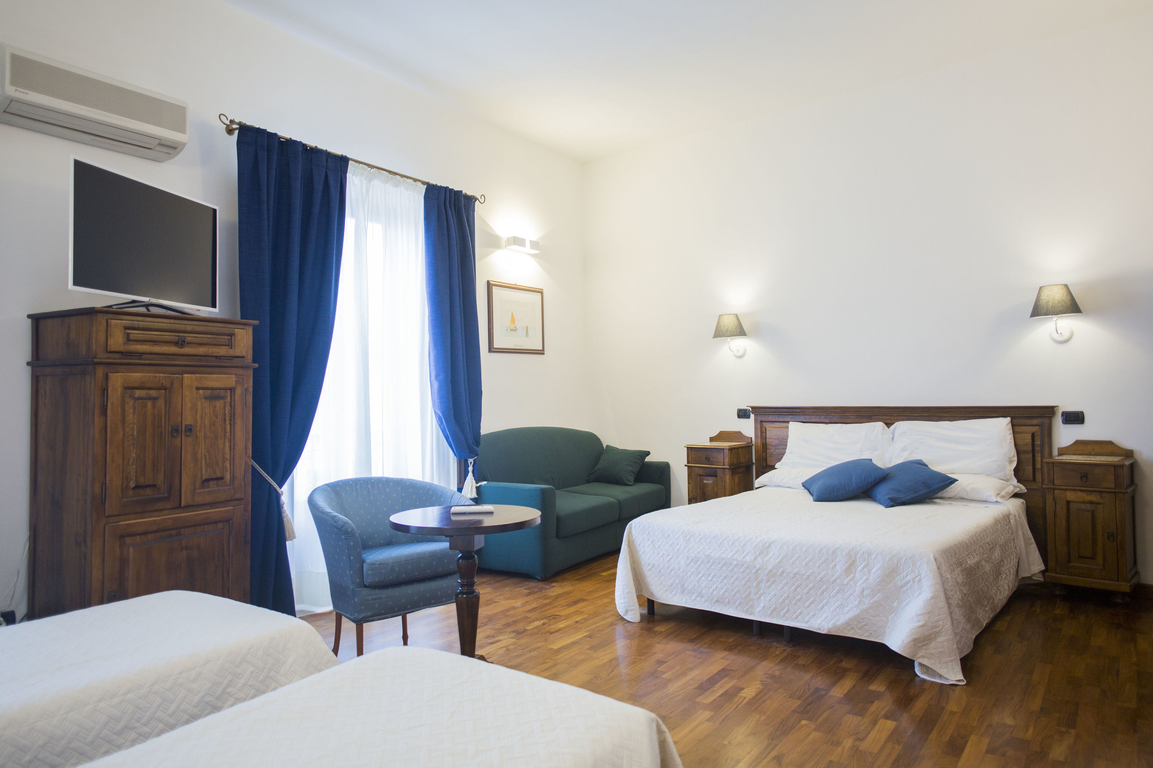 Hotelkamer met een bed, twee nachtkastjes, een stoel, een klein tafeltje, een kledingkast en een televisie.