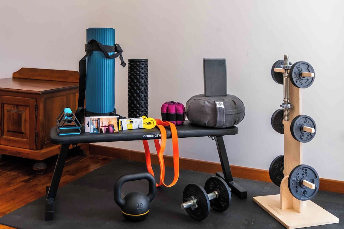 Ein Home-Gym-Einrichtung mit Kettlebell, Hanteln, einer Yogamatte, einer Kettlebell-Tasche, einer Yogamatten-Tasche und einem Kettlebell-Ständer.