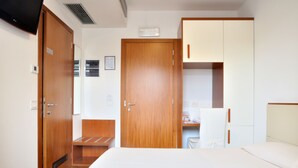 Una habitación de hotel con cama, escritorio, silla y armario.