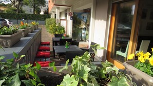 Una terraza con mobiliario exterior, plantas en macetas y vistas a un canal.