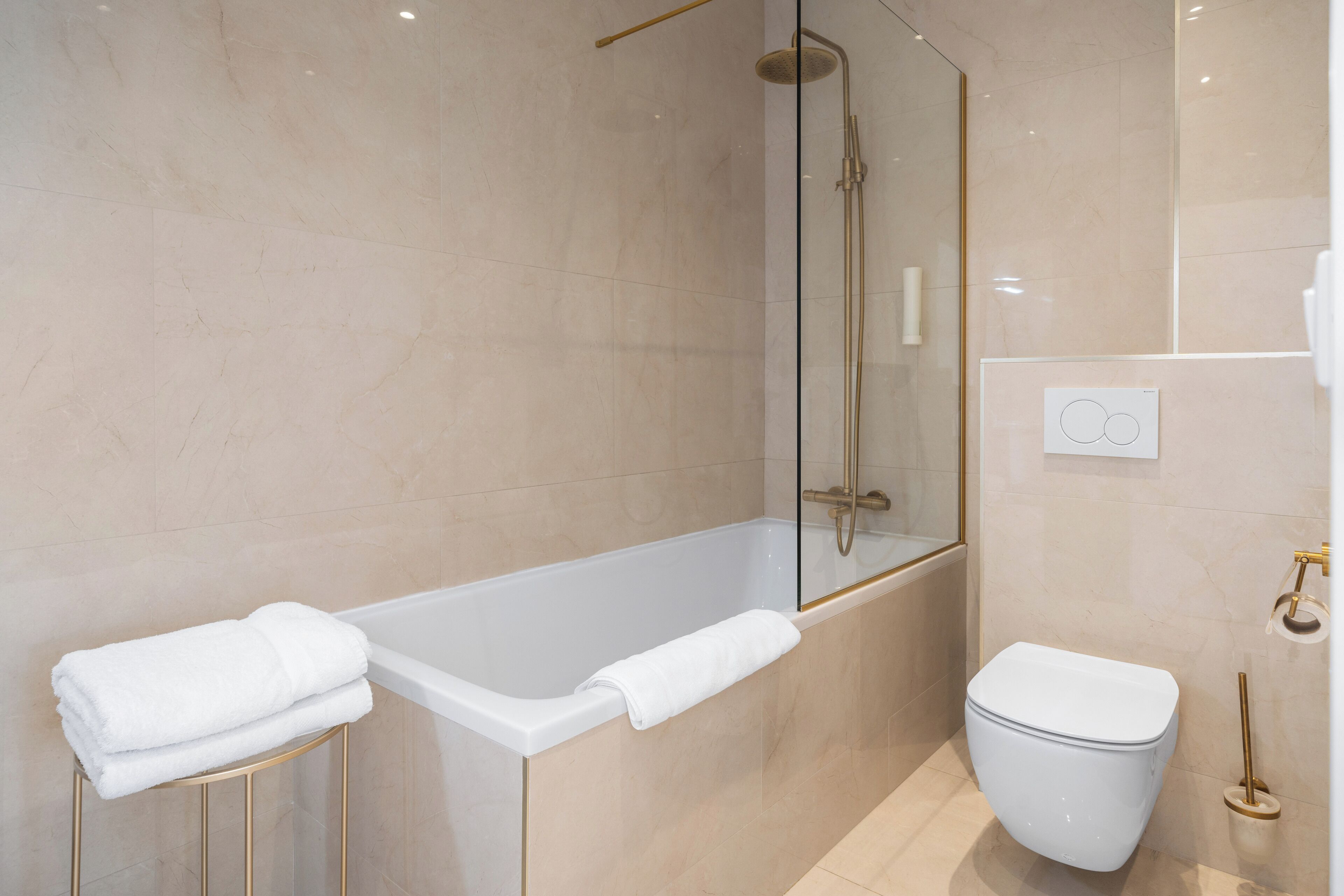 Een moderne badkamer met een badkuip, toilet en een douchecabine met glazen wanden.
