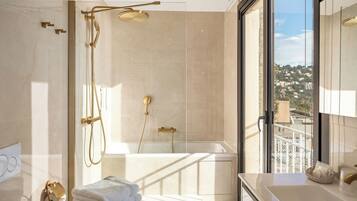 A modern bathroom with a glass-enclosed shower, a bathtub, and a view of a cityscape through a large window.
