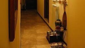 A narrow hallway with a wooden door at the end, a radiator, and a small table with items on it. - La Dimora di Nettuno (Naples)