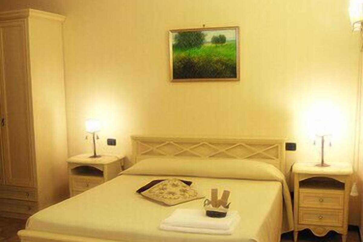 Ein ordentlich eingerichtetes Hotelzimmer mit einem großen Bett, zwei Nachttischen und einem Bild an der Wand.