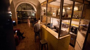 Een bar met barkrukken, een toonbank en planken met flessen.
