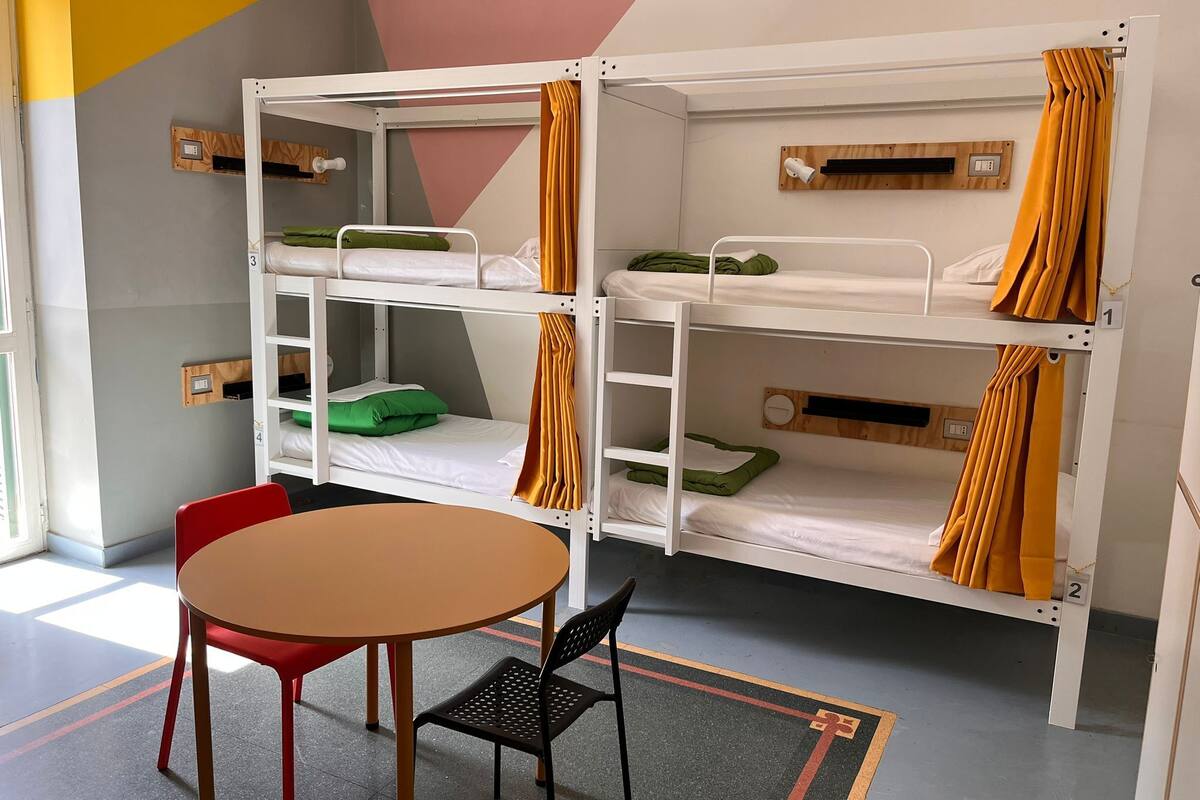 Une chambre avec des lits superposés, une table et des chaises.