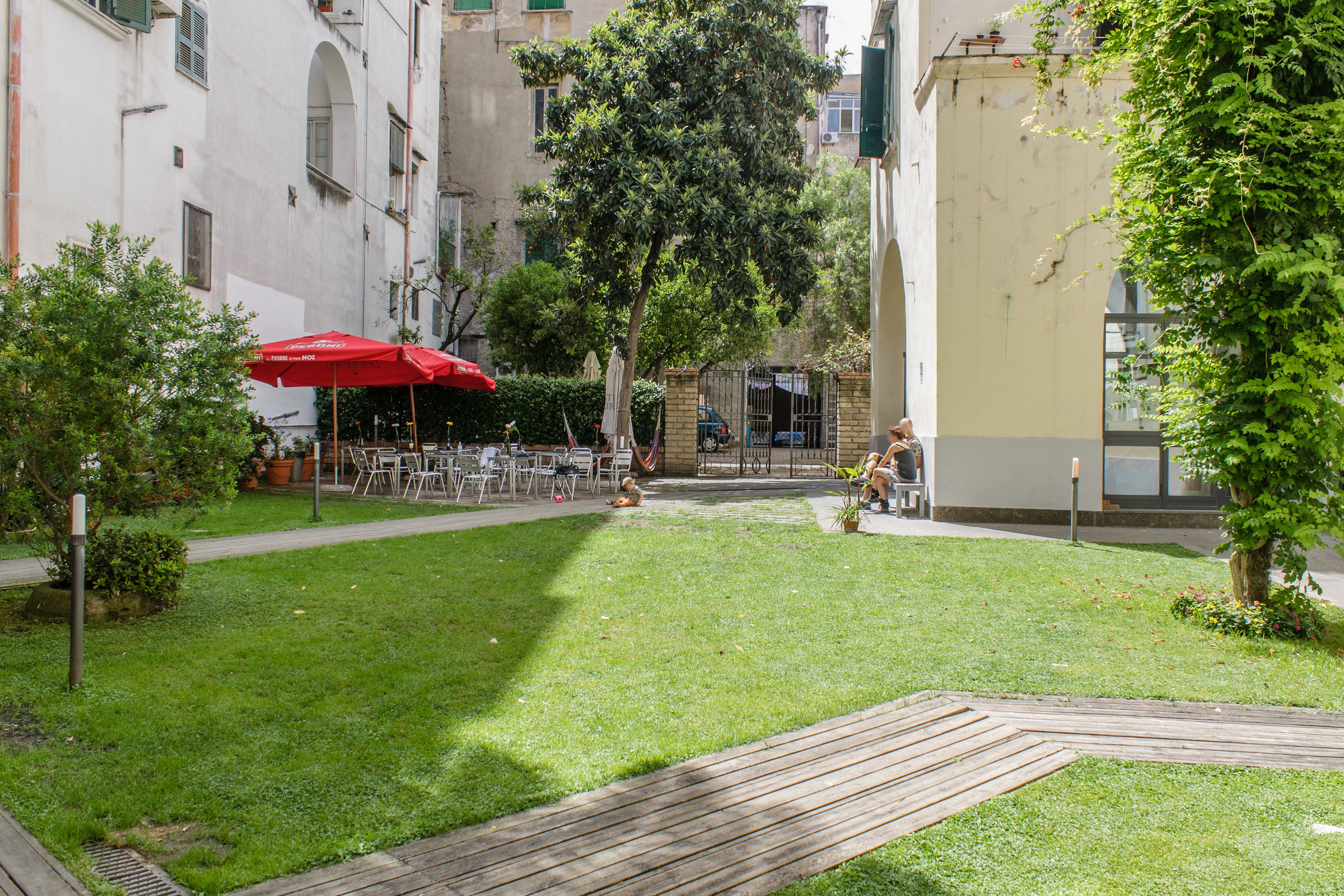 Un patio con césped, mobiliario exterior y un paraguas rojo.