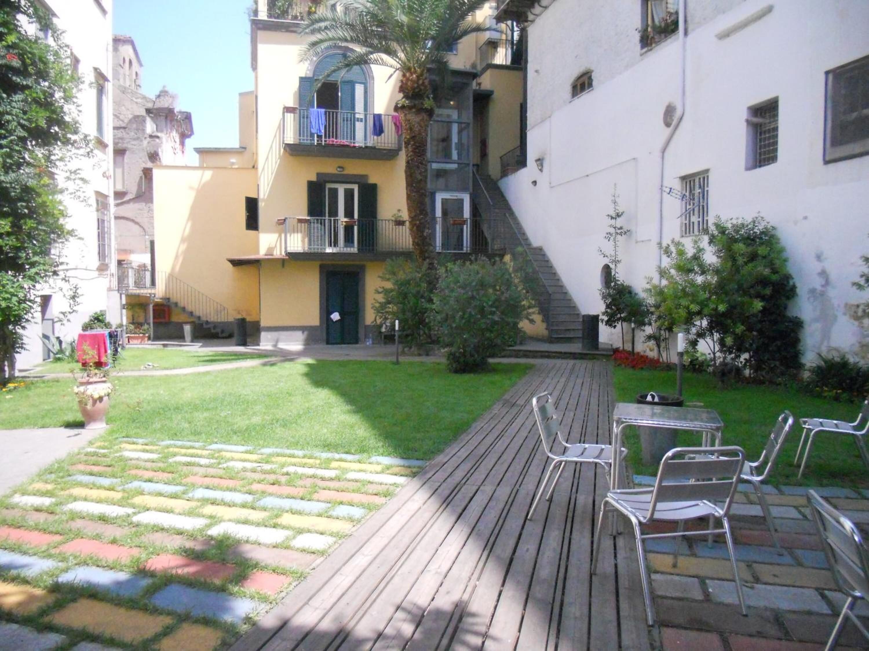 Une cour dotée d’une terrasse en bois, d’un espace salon extérieur et d’un petit jardin.
