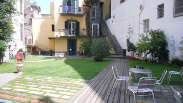 Une cour dotée d’une terrasse en bois, d’un espace salon extérieur et d’un petit jardin.