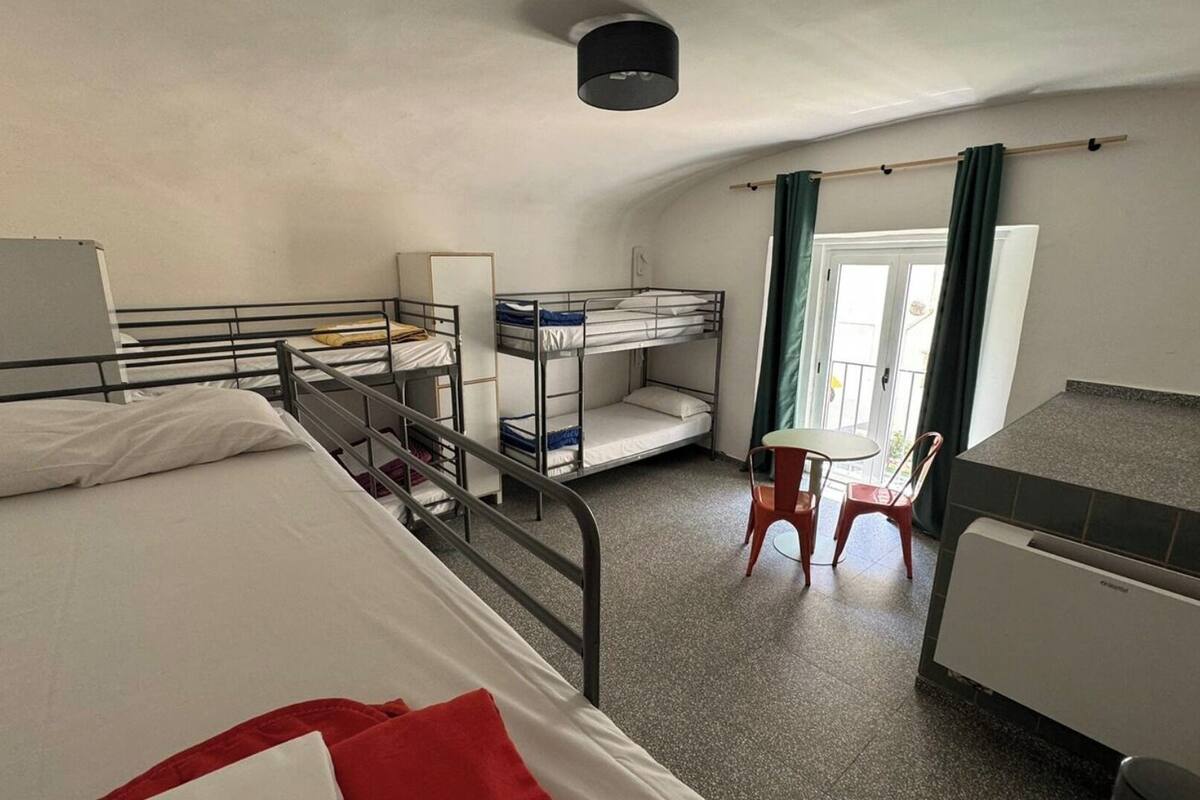 Une chambre de dortoir avec des lits superposés, un bureau, une chaise et un radiateur.