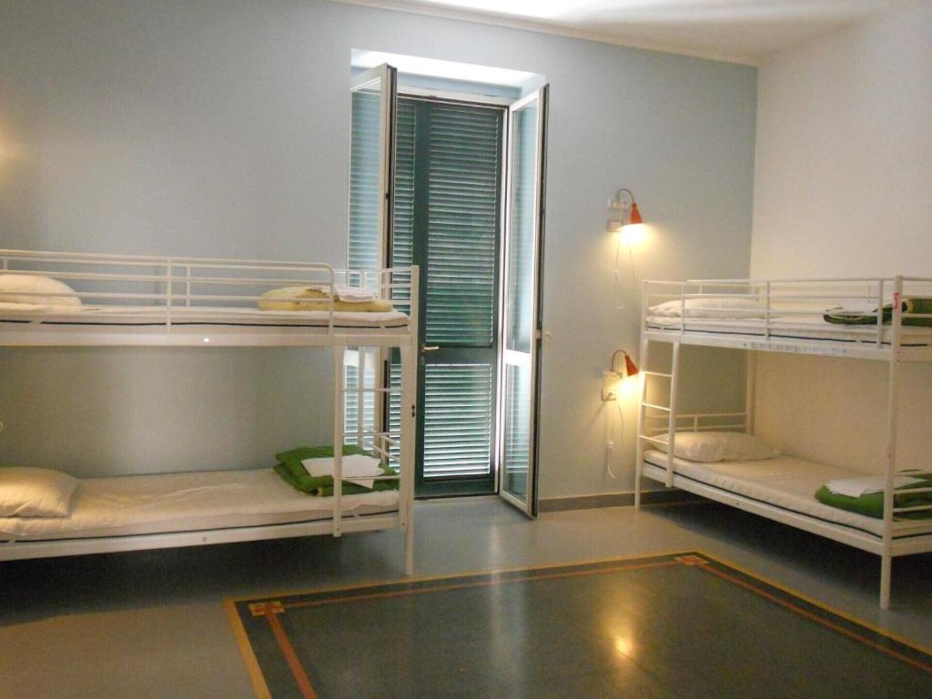 Ein Schlafsaalzimmer mit Etagenbetten, einer Tür und einer Wandleuchte.