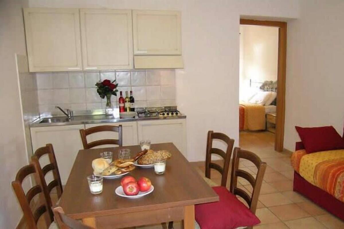 A compact kitchen with a dining table set for two, a sofa, and a small living area.