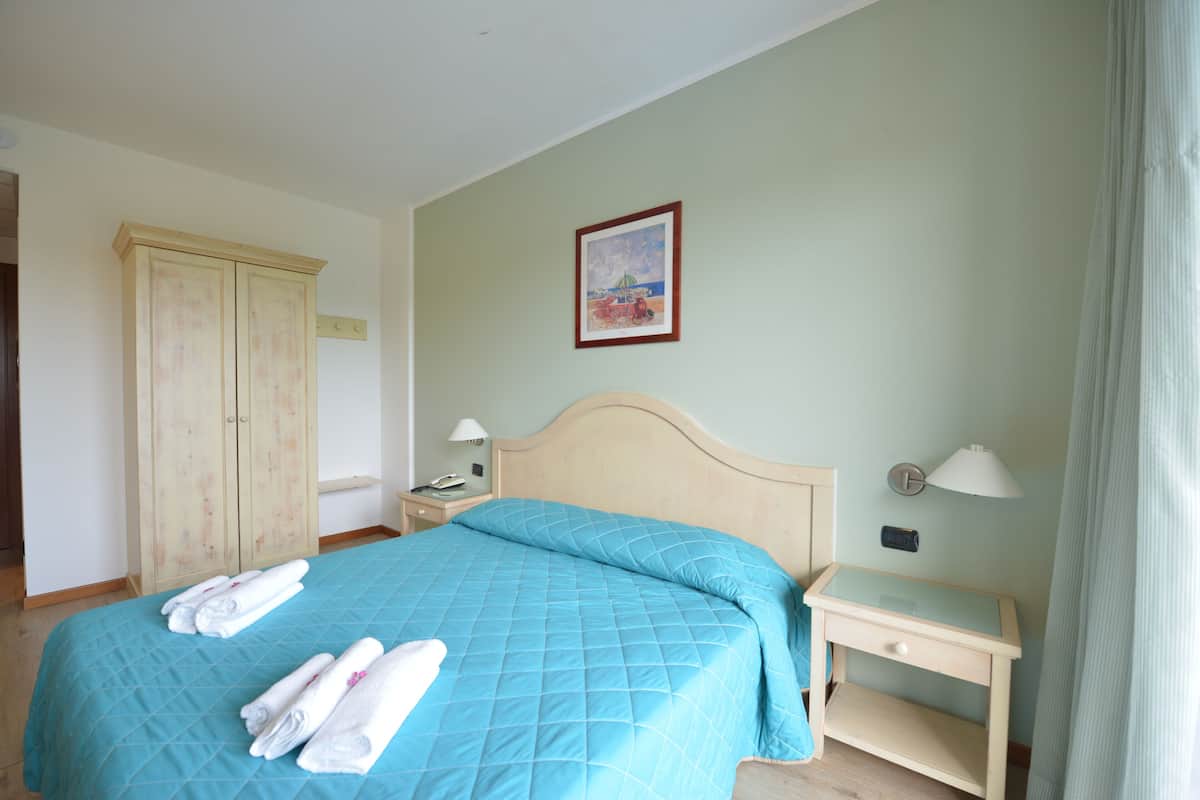 A bedroom with a bed, a nightstand, a bedside table, a wardrobe, and a painting on the wall.