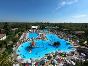A large outdoor swimming pool area with multiple pools, water slides, and sun loungers. - Hotel Bella Italia (Peschiera del Garda)